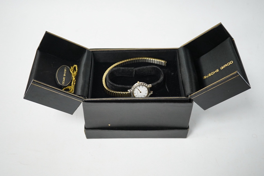 A lady's modern 9kt Bueche Girod quartz wrist watch, with diamond set bezel, case diameter 25mm, on a steel and gold plated flexible bracelet (detached), with Bueche Girod box. Condition - poor to fair